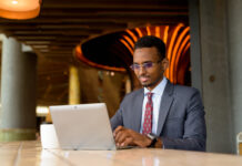 Como automatizar o seu negócio: 5 estratégias simples Portrait of African businessman wearing suit and tie in coffee shop